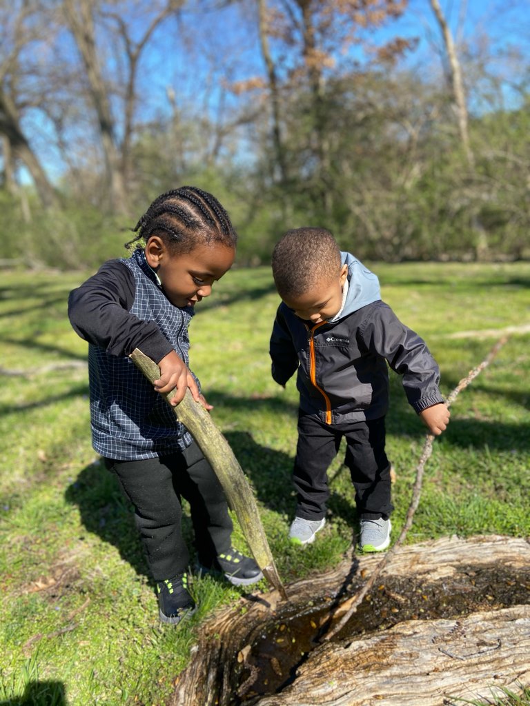 two children playing with sticks outside